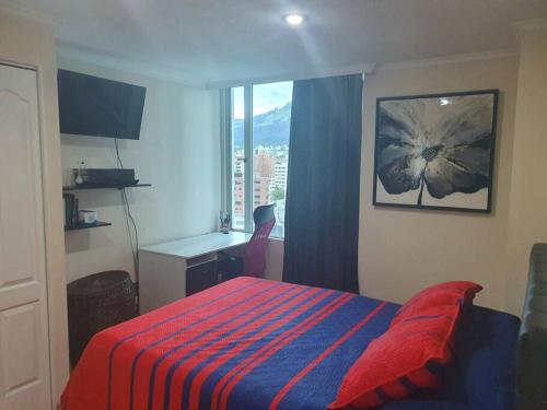1 dormitorio con 1 cama con manta roja y azul en Bella Suit amoblada, sector exclusivo La Carolina., en Quito