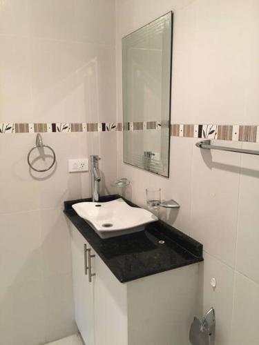 a white bathroom with a sink and a mirror at Bella Suit amoblada, sector exclusivo La Carolina. in Quito