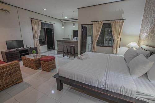 a bedroom with a white bed and a living room at Panorama Cottages I in Legian