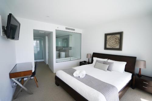 una camera da letto con un letto, una scrivania e una televisione di Oracle Broadbeach - Amazing Ocean Views! a Gold Coast