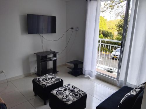 sala de estar con sofá, TV y ventana en Apartamento Amoblado Conjunto Terraverde, en Ibagué