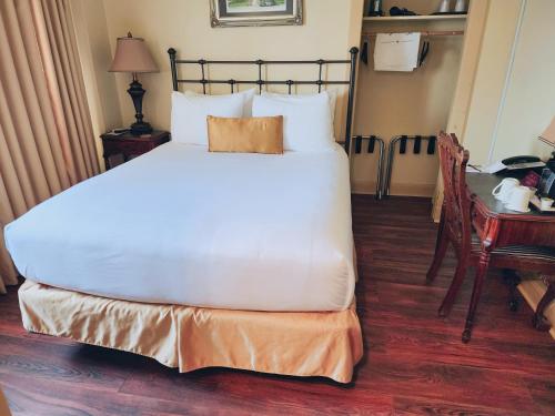 a bed in a hotel room with a desk and a bed at The Faust Hotel in New Braunfels