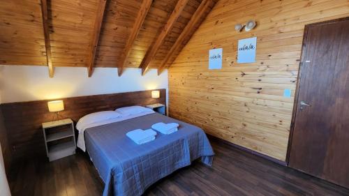 1 dormitorio con 1 cama y pared de madera en Valle Florido 2 en Trevelin