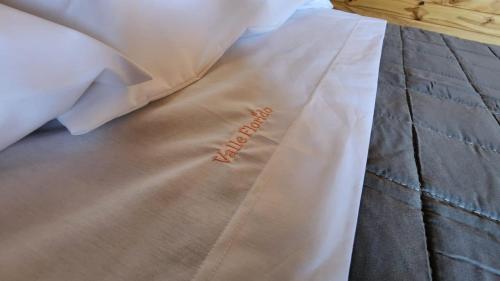 a bed with a white comforter with a writing on it at Valle Florido 2 in Trevelin