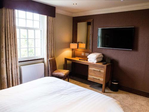 a hotel room with a bed and a desk with a television at Busby Hotel in Busby