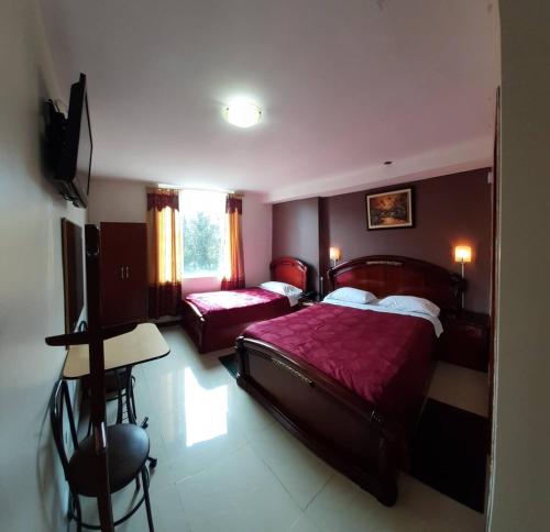 a bedroom with two beds and a desk and a television at Hotel Del River in Hacienda Carriona