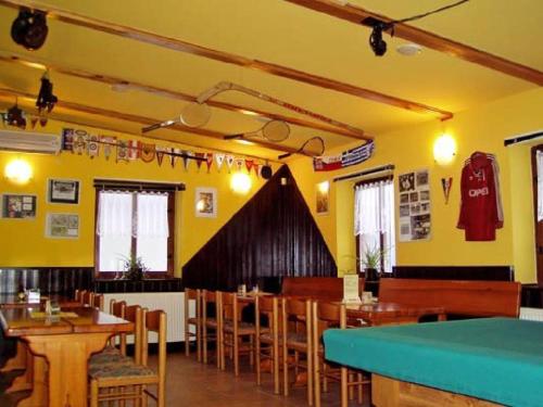 ein Restaurant mit Holztischen und -stühlen und gelben Wänden in der Unterkunft Restaurace a Penzion u Vladaru in Mikulášovice