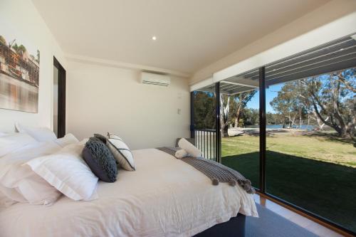 een slaapkamer met een wit bed en een groot raam bij River Chillin - Waterfront Holiday Home - Echuca Holiday Homes in Moama