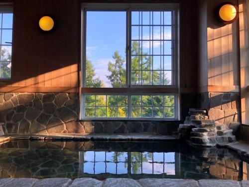 Una piscina en una habitación con ventanas y una ventana que refleja en Koguriyama Sanso - Vacation STAY 37452v en Minami Uonuma