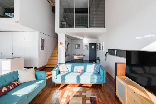 a living room with a blue couch and a tv at Radiant Richmond Warehouse in Melbourne