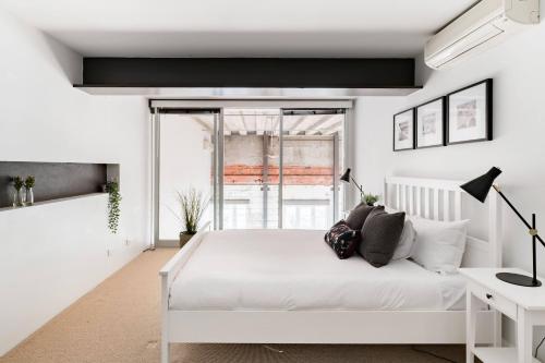 a white bedroom with a white bed and a window at Radiant Richmond Warehouse in Melbourne