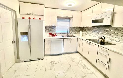 a kitchen with white cabinets and a refrigerator at 3 miles to Siesta Key #1 Beach in America in Sarasota