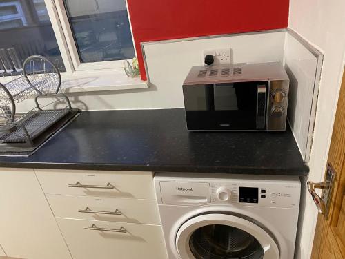 a kitchen with a microwave and a washing machine at The Vacationers - Pvt Rooms with Shared Bath in Sunderland