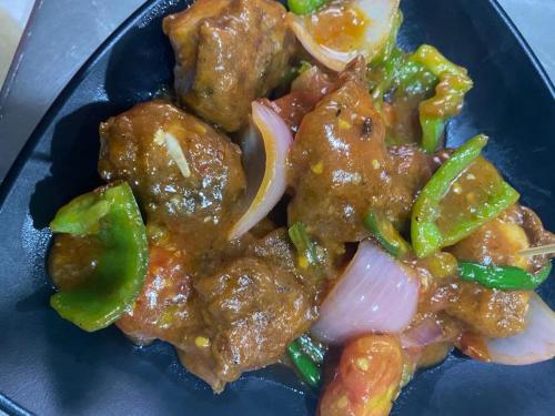 a blue plate of food with meat and vegetables at Hotel Aagaman - Best Family Hotel in Bandipur in Bandīpur