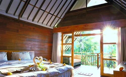 a bedroom with two beds and a large window at Village Above The Clouds in Bedugul
