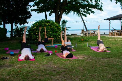 um grupo de pessoas fazendo yoga na grama em Colorful Hut em Haad Pleayleam