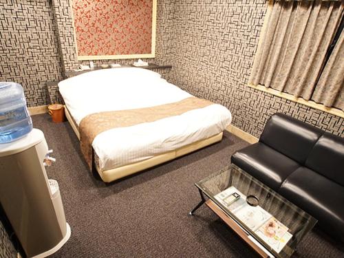 Cette chambre comprend un lit, un canapé et une chaise. dans l'établissement フラミンゴ　大人専用, à Yoshioka