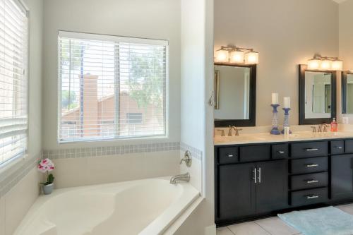 baño con bañera, 2 lavabos y ventana en Luxe on the Links, en Phoenix