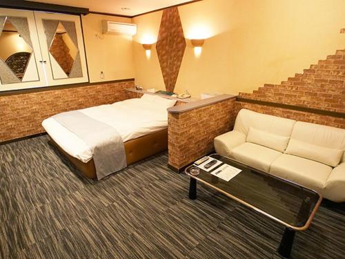 um quarto de hotel com uma cama e um sofá em グリーンヒル　大人専用 em Yoshioka