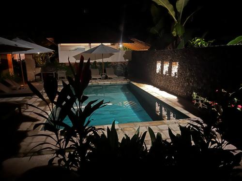 a swimming pool at night with an umbrella at Rumah Kelapa Senang in Karangasem