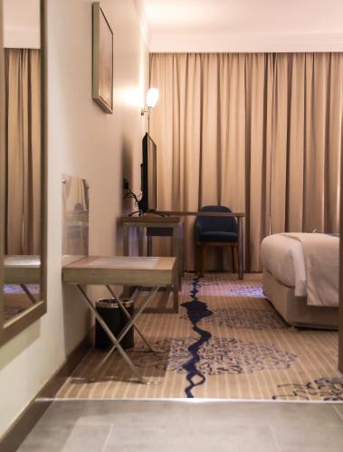 a hotel room with a bed and a desk at Safwat Alkhobar Hotel in Al Khobar