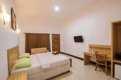 a bedroom with a bed and a desk and a table at Central Inn Senggigi in Senggigi
