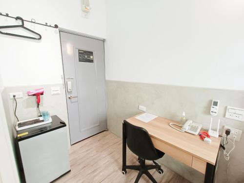 um escritório com uma secretária, um frigorífico e uma mesa em No 9 Hotel-九號文旅 em Tainan