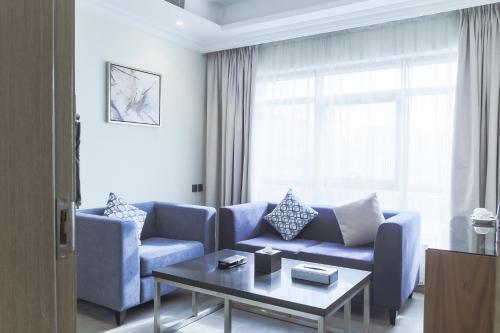 a living room with a blue couch and a table at Safwat Alkhobar Hotel in Al Khobar
