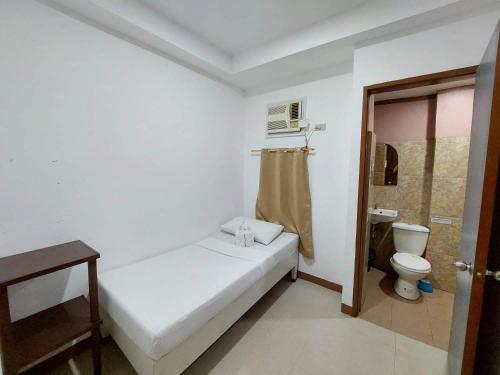 a small white room with a bed and a toilet at Island Hop Inn in El Nido
