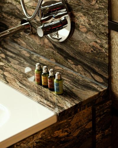 three bottles of essential oils sitting next to a sink at Hotel Monopol in Katowice