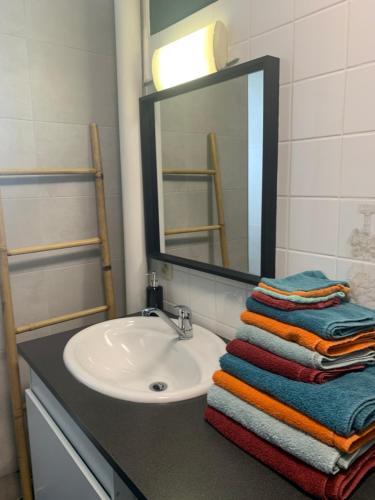 W łazience znajduje się umywalka, lustro i ręczniki. w obiekcie Appartement tout confort dans une résidence calme w mieście Givet
