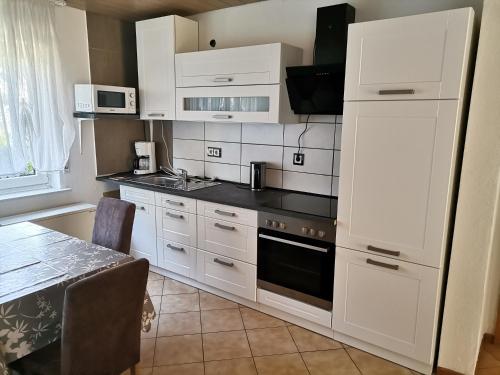 a kitchen with white cabinets and a stove top oven at Ferienhaus Happel in Bad Endbach