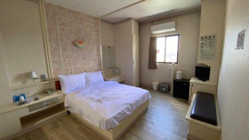 1 dormitorio con cama blanca y ventana en 日日 Meworld en Beigang