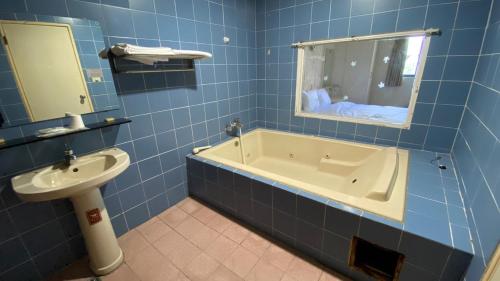 ein Badezimmer mit einer Badewanne, einem Waschbecken und einem Spiegel in der Unterkunft 日日 Meworld in Beigang