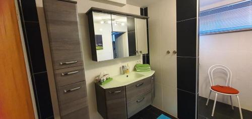 La salle de bains est pourvue d'un lavabo et d'un miroir. dans l'établissement Schöne Ferienwohnung mit Terrasse und Garten, à Überherrn