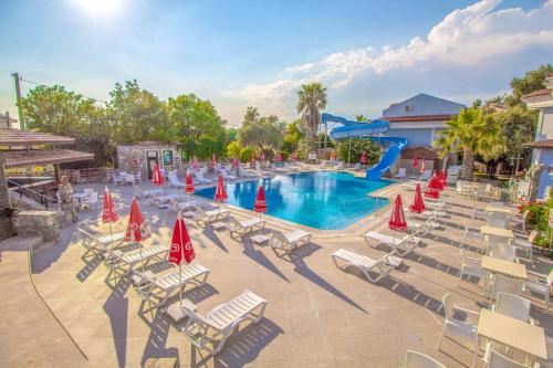 - une piscine avec des chaises et des parasols dans un complexe dans l'établissement Zehra Tatil Köyü- Halal All Inclusive, à Muğla