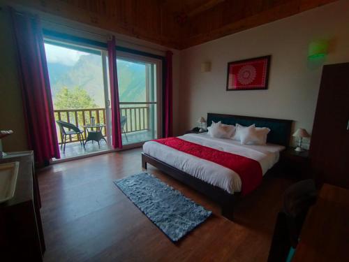 a bedroom with a bed with a view of a balcony at Satopanth The Auli Resort By Royal Collection Hotels in Joshīmath
