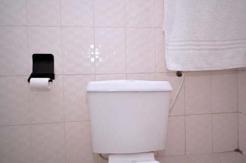 a white bathroom with a toilet and a roll of toilet paper at Golden One-bedroom serviced apartment with free WiFi in Kisii