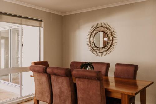 a dining room with a wooden table and a mirror at Saltwater Villas - Pet Friendly Accommodation in Mooloolaba