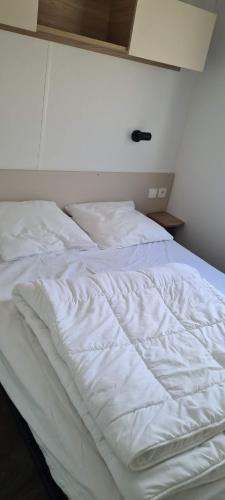 an unmade bed in a room with white sheets at Mobil home Amira 3 Trigano in Saint-Jean-de-Monts