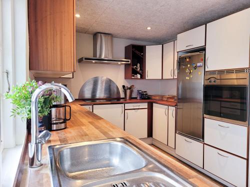 a kitchen with white cabinets and a stainless steel sink at Sunbjerre B&B in Lille Dalby