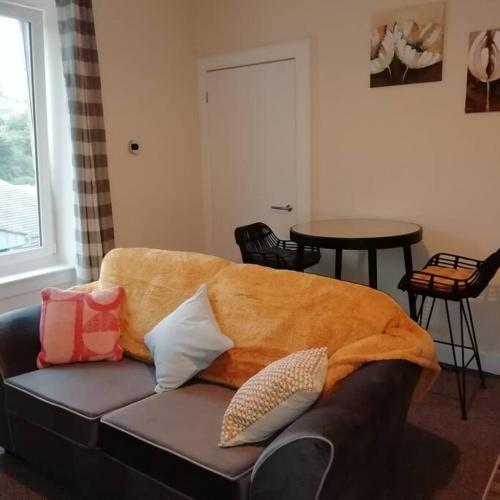 un sofá con una manta en la sala de estar en Carvetii - Norman House - 2nd floor, 1 bedroom flat en Boʼness