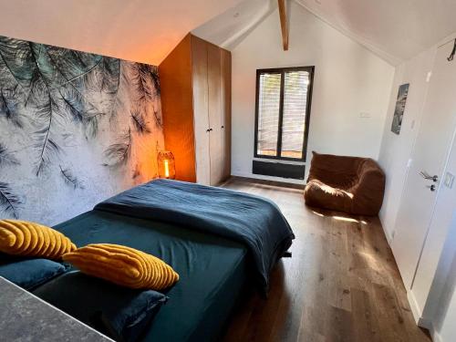 1 dormitorio con 1 cama y 1 silla en una habitación en Le cache a l eau, en Le Pouliguen