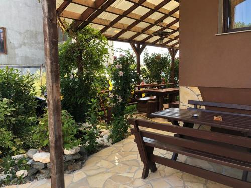 a patio with a wooden bench and tables and plants at Pensiunea Tisa in Baile Felix