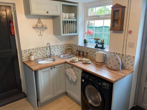 a kitchen with a sink and a washing machine at 18th Century Cottage with Stunning Views in Stratford-upon-Avon
