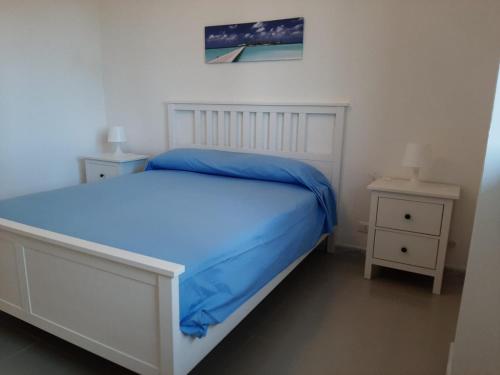a bedroom with a bed with blue sheets and two night stands at Villa Marna Bianca in Borgo Bonsignore