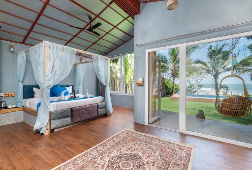 a bedroom with a bed and a view of the ocean at Amadi Beach Front Resort in Mandrem