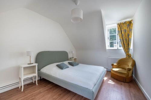 ein kleines Schlafzimmer mit einem Bett und einem Stuhl in der Unterkunft L'Annexe du Manoir - A proximité de Carantec in Taulé