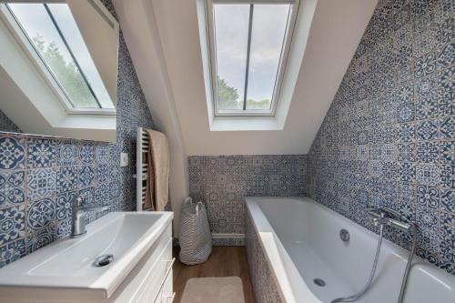 a bathroom with a tub and a sink and two windows at L'Annexe du Manoir - A proximité de Carantec in Taulé