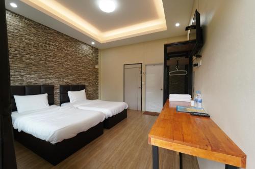 a room with two beds and a wooden table at Chillax Khaosok Hostel - SHA Certified in Khao Sok
